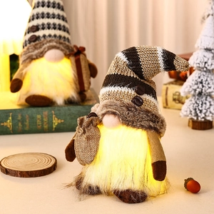 Close-up of glowing Christmas coffee gnome with LED light and striped knit hat decor
