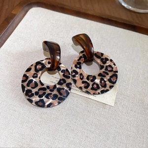 Close-up of leopard print resin hoop earrings on beige fabric background