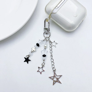 Close-up of Y2K silver star and cross charms on a white wireless headphone case
