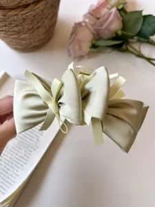 Detail of light green satin layered bow hair claw clip showing elegant French style fabric