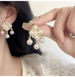 Detail of luxury pearl tassel earrings with zircon inlay and golden metallic finish