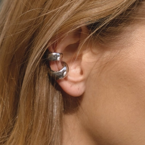 Close-up of dual silver polished stainless steel ear cuffs worn on the outer cartilage