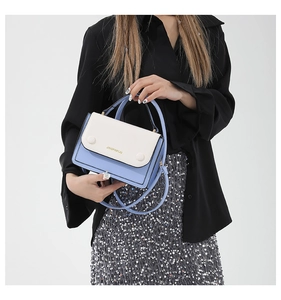 Détail du sac à main bicolore bleu et blanc avec poignée supérieure et logo de la marque