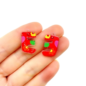 Colorful acrylic letter E floral pendant charms held by hand for jewelry making