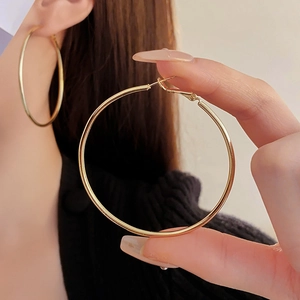 Close-up of minimalist gold hoop earrings showing circular metal design and glossy finish