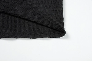 Macro du tissu en maille plissée noire montrant le détail de la double couture de précision