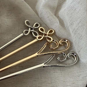 Golden and silver alloy hairpins with Ruyi heart pattern on beige linen fabric