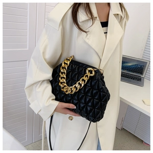 Detail of black quilted shell bag featuring chunky gold chain and slim shoulder strap