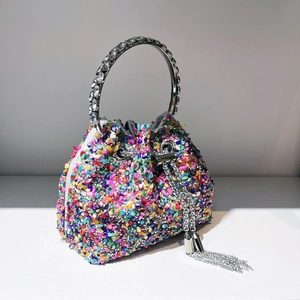 Detailed view of colorful rhinestone bucket bag with silver metal ring handle and tassels