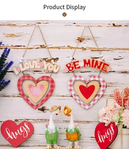Dettaglio di pendenti in legno per San Valentino con motivi a quadri e figure di coppie di oche
