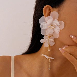 Dettaglio di eleganti orecchini a nappa con fiori in chiffon bianco indossati da una modella