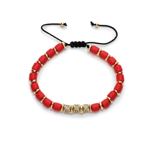 Rotes Perlenarmband mit Goldakzenten und mikroverzierten Kristallzylindern auf Weiß