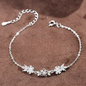 Detailed close-up of silver floral bracelet featuring white sparkling stones and round link chain