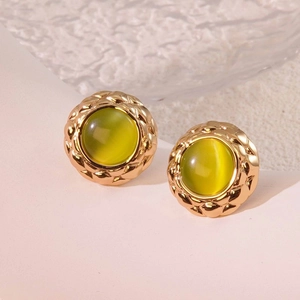 Macro view of vintage gold stud earrings with green cat-eye stone and diamond pattern