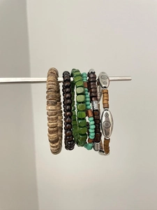 Detailansicht von Ethno-Holzperlenarmbändern mit Türkis-Akzenten an einem Display