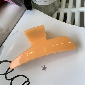 Top view of large translucent light orange hair claw clip in a moon-shaped design