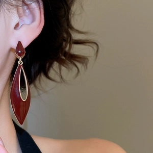 Close-up of elegant deep red hollow waterdrop earrings worn by a model in a luxury setting