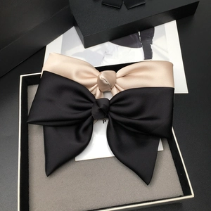 Detailed view of large black and champagne satin bow hair clips in a premium gift box