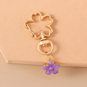 Detailed macro view of a purple enamel flower pendant on a golden clover keychain