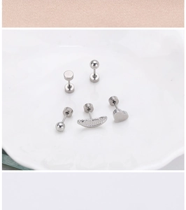 Close-up of stainless steel stud earrings in heart, feather, and geometric shapes.