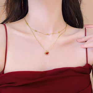 Close-up of double-layer gold necklace with red enamel heart pendant on a model