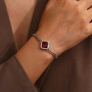 Nahaufnahme eines silbernen Panzerarmbands mit quadratischem rotem Zirkon am Handgelenk