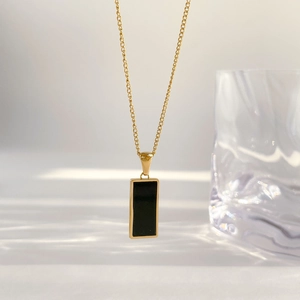 Detail shot of a minimalist double-layer gold necklace with black geometric pendants