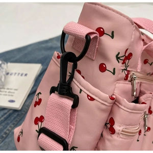 Close-up of pink tote bag stitching with cherry print and durable strap buckle