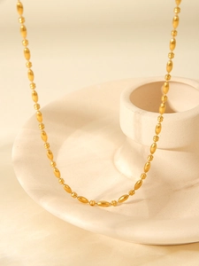 Close-up of 18K gold plated stainless steel oval bead chain on a ceramic display