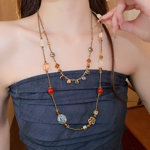 Détail d'un collier multicouche avec perles rouges, verre et fleurs dorées vintage