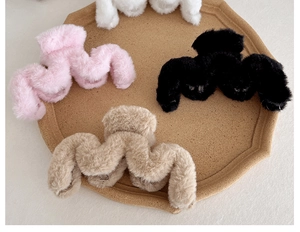 Detail of 14cm large plush hair claws in pink black beige and white on a wooden tray