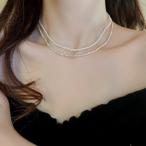 Close-up of a layered necklace featuring white pearls and a silver irregular link chain