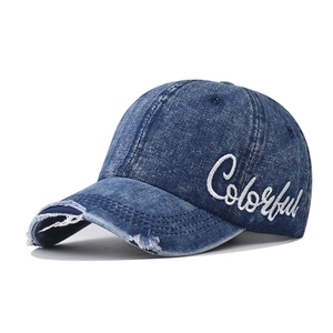 Close-up of washed blue denim baseball cap featuring white Colorful cursive embroidery