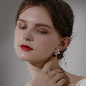 Elegant camellia stud earrings with cream-colored petals worn by a model in a side view
