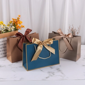 Elegant paper gift bags with satin bows and rope handles in blue, brown, and grey colors