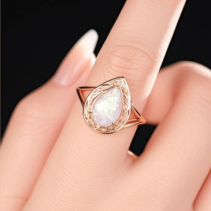 Makroaufnahme von Tropfen-Opal-Ring mit Roségold-Filigran an der Hand des Models