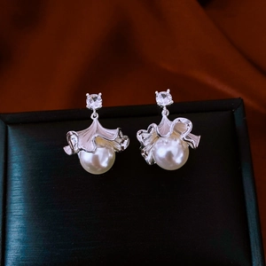 Close-up of silver flower petal earrings with white pearls and sparkling zircon accents