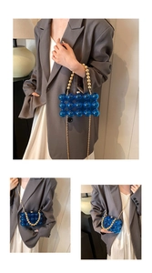 Close-up of blue acrylic bubble bag with golden pearl handle and metal chain strap