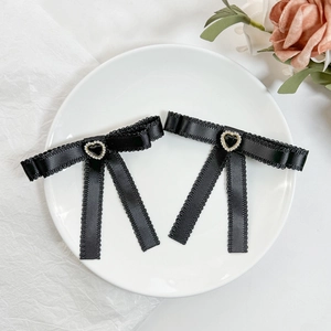 Détail de barrettes à nœuds noirs avec pierre précieuse en cœur et accents dorés
