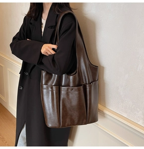 Close-up of a dark brown PU leather tote bag with functional exterior pocket detail