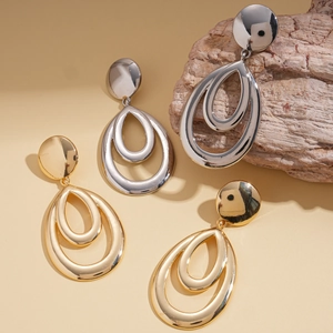 Metallic geometric hollow teardrop earrings in gold and silver finishes on a textured wood block