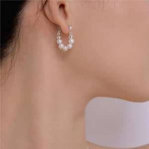 Elegant C-shaped pearl earrings on model featuring white and transparent beaded details