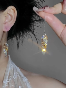 Detailed view of long tassel earrings with champagne crystal clusters and silver needle