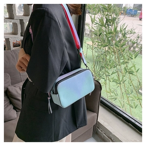 Detail of colorful gradient camera bag with wide strap and tassel zipper on a female model
