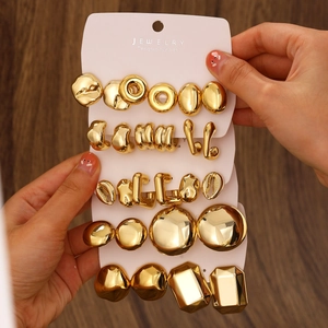 Detailed macro view of gold-colored geometric earring set held against a dark wood background