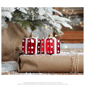 Close-up of two red Christmas gift box ornaments with snow details on pine branches
