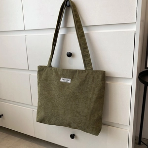 Macro view of olive green corduroy tote bag texture with white fashion label