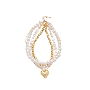 Collier de perles multicouche avec pendentif coeur doré et perles baroques sur fond blanc