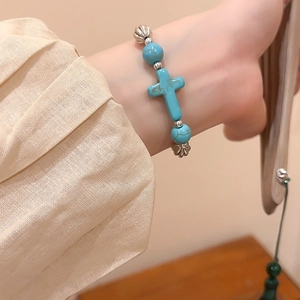 Macro view of vintage beaded bracelet featuring turquoise cross and retro silver spacers