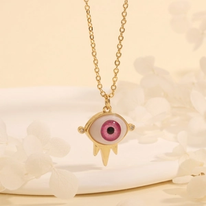 Detailed close-up of a 18K gold plated evil eye pendant with pink iris and golden spikes